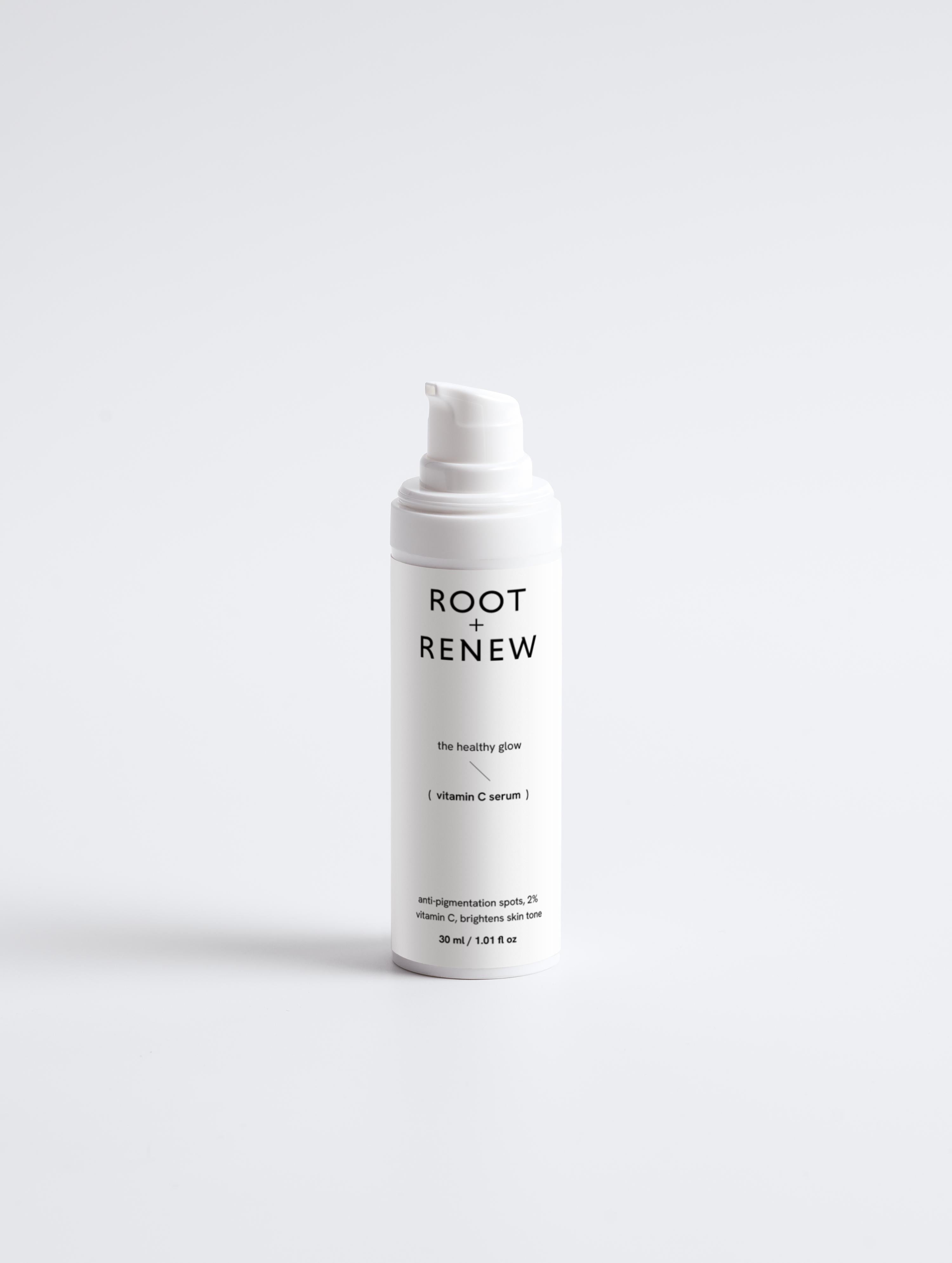Front-facing bottle of Root + Renew The Healthy Glow serum with pump, labeled to target pigmentation and brighten skin tone