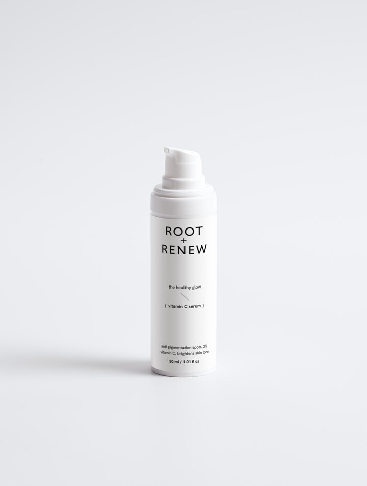 Front-facing bottle of Root + Renew The Healthy Glow serum with pump, labeled to target pigmentation and brighten skin tone