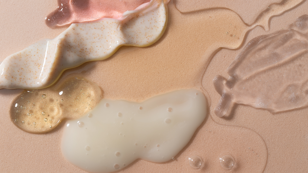 Editorial flat lay of skincare textures — creamy exfoliant, luminous gel, and hydrating serum — layered on a soft nude background showing the contrast of formulas and finishes.