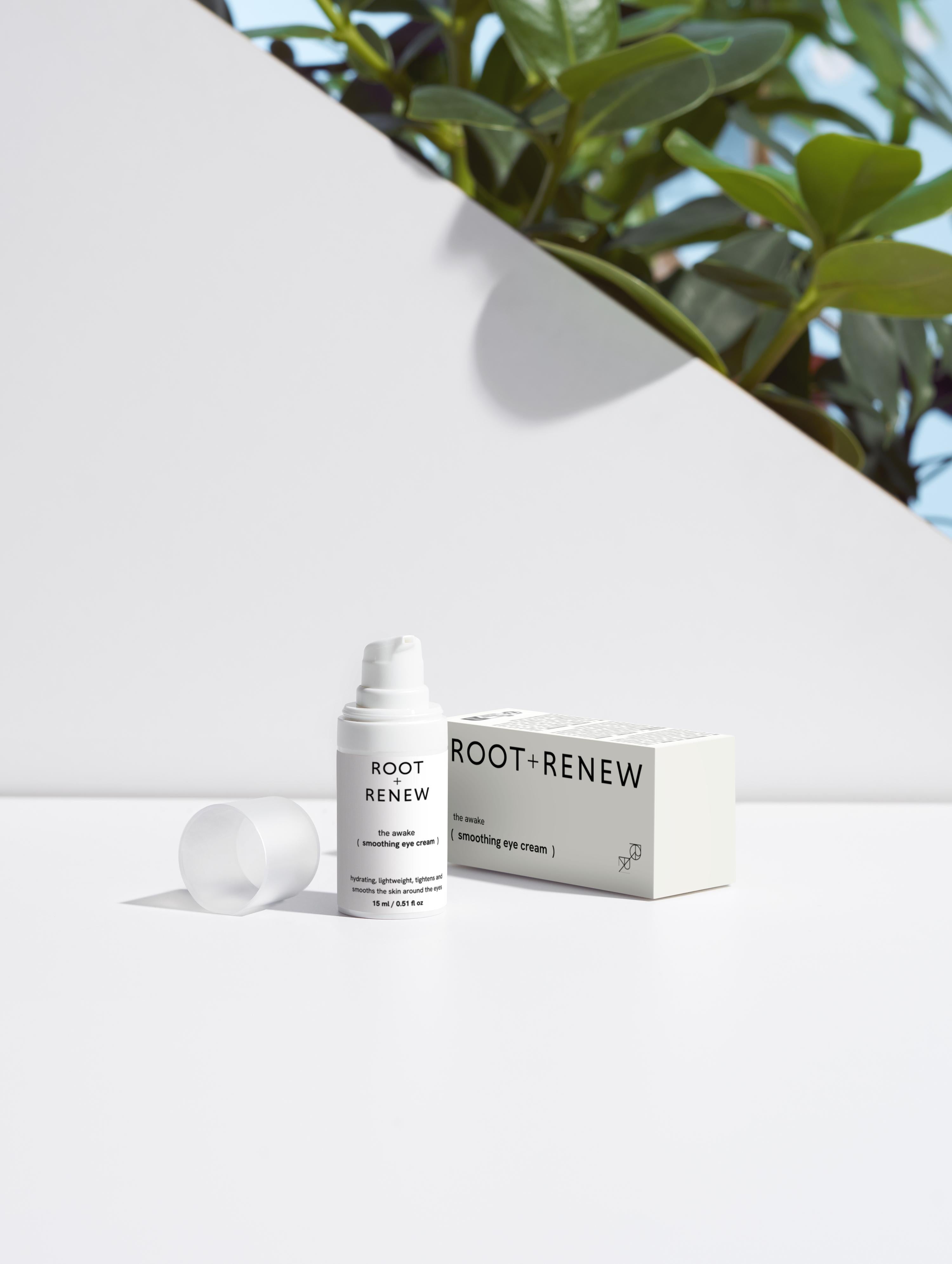 The Awake Eye Cream and its packaging shot in a bright studio setup with natural green plants in the background, emphasizing freshness and vitality.