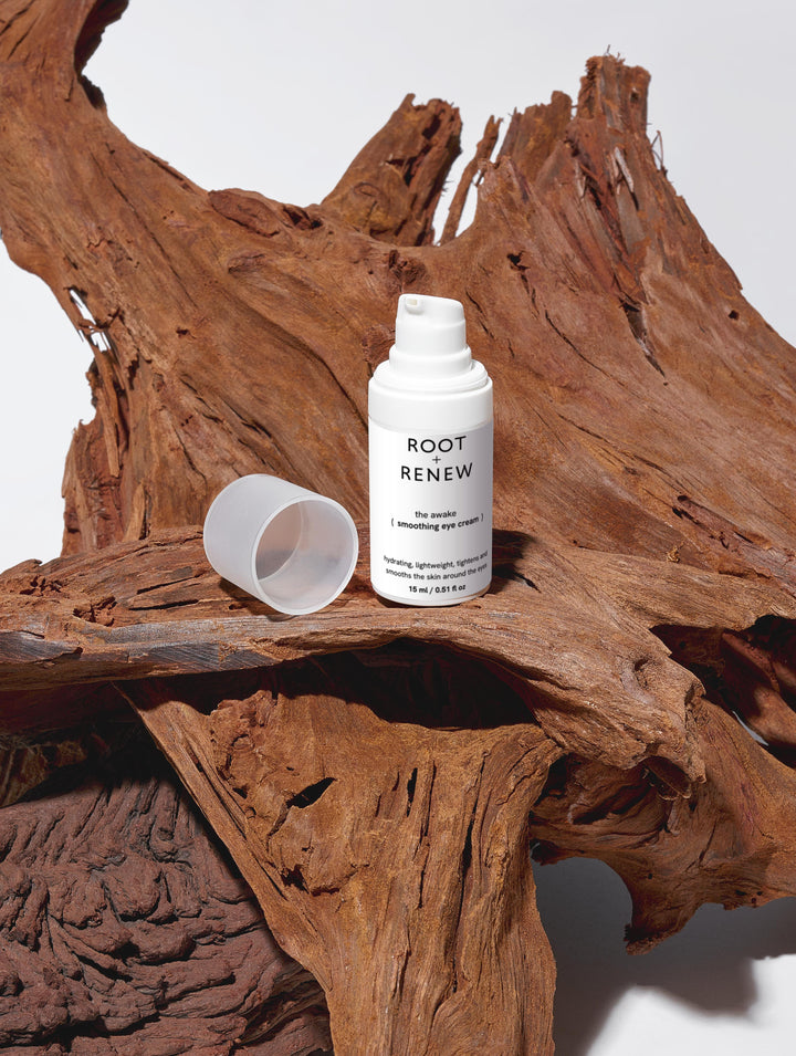 The Awake Smoothing Eye Cream placed on rich, textured red wood, highlighting its earthy, grounded identity.